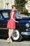 Beautiful young woman in vintage dress with retro auto