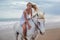 Beautiful young woman walking with horse at the beach, horseback