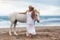 Beautiful young woman walking with horse at the beach, horseback