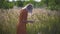 Beautiful young woman walks in the field collects a bouquet of flowers and spikelets. Portrait of attractive female on grass at su