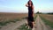 A beautiful young woman walks with a Staffordshire Terrier in a field. Happy free girl on a walk with a dog in nature.