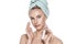 Beautiful young woman wearing head towel using natural moisturizer, face serum or anti aging cream. Facial treatment concept.