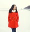 beautiful young woman wearing a red coat and scarf over snow in winter