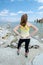 Beautiful young woman wearing a tank top and yoga pants poses with back facing the camera at Mono Lake in California