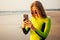 Beautiful and young woman in a wetsuit holding a smartphone and photographing the landscape of paradise beach.swimmer