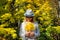 Beautiful young woman in white clothes and hat tilted her head to the bouquet of yellow leaves in her hands. Elegant blonde, face