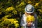 Beautiful young woman in white clothes and hat tilted her head to the bouquet of yellow leaves in her hands. Elegant blonde, face