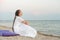 Beautiful young woman in white clothes sitting on sandy beach and enjoy silence