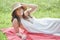 Beautiful young woman in white dress on picnic blanket on summer afternoon