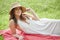Beautiful young woman in white dress on picnic blanket on summer afternoon