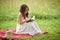 Beautiful young woman in white dress on picnic blanket on summer afternoon