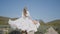 Beautiful young woman in white dress runs across field. Action. Woman's hair and dress flutter beautifully while running