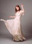 Beautiful young woman in white evening dress with floral print. Studio portrait of ginger girl in evening gown