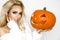 Beautiful young woman in white sweater, standing on white background and holding pumpkin;