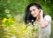Beautiful young woman in wild flowers field.Portrait of attractive brunette girl with long hair relaxing in nature, outdoor shot