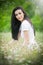 Beautiful young woman in wild flowers field.Portrait of attractive brunette girl with long hair relaxing in nature, outdoor shot