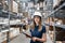 Beautiful young woman worker of furniture store in shopping center. Girl looking for goods with a tablet is checking