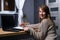 Beautiful young woman working on her personal laptop with black mock up screen, in home office, looking to camera, smiling cute