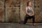 Beautiful young woman workout doing lunge step inear rusty door