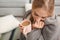 Beautiful young woman wrapped in plaid sitting with cup of coffee on floor at home.