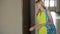 Beautiful young woman in yellow dress opening the door with keys and entering her apartment