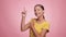 Beautiful young woman in a yellow t-shirt  laughs and dances on a pink background