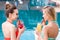 beautiful young women drinking delicious fruit beverages at poolside