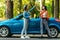 Beautiful young women giving high five, having fun together, cheering with raised arms driving modern convertible car on summer