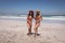 Beautiful young women with hat and sunglasses dancing at beach in the sunshine