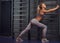 Beautifull fitness woman does stretching leaning on a wall bars in the modern fitness center.