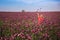 Beautifull happy woman with long hair in red dress lonely walking in the Lilac Poppy Flowers field