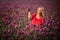 Beautifull happy woman with long hair in red dress lonely walking in the Lilac Poppy Flowers field