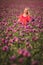 Beautifull happy woman with long hair in red dress lonely walking in the Lilac Poppy Flowers field