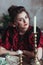 Beautifull woman in black-red dress sitting in restaurant at rustic table with dishes, sackcloth and candle