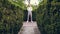 Among the beautifully cropped bushes in the park, a young man in a white shirt, trousers, stylish suspenders and bow tie