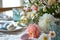 Beautifully decorated Easter dinner table with colorful flowers, pastel crockery and dyed eggs. Indoor Easter celebration party