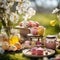 beautifully decorated outdoor table in bright daylight set with plates, glasses, and flowers for a easter picnic