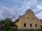 Beautifully decorated yellow rural farmstead house with some blooming flowers on the left side