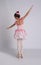 Beautifully dressed little ballerina dancing on grey background, back view