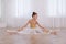 Beautifully dressed little ballerina stretching in studio