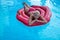 Beautifully gorgeous lady in red bathing suits on inflatable mattress red rose floating in the pool and elegant hotels, summer