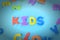Beautifully laid out inscription kids of multi-colored letters. Background with vignette.