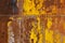 beautifully rusted rivetted sheet metal with leftovers of yellow paint texture and full-frame background