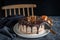 Beautifully styled and decorated birthday cake with no candle, on a table with chair in the background, oranges, walnut and