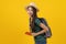 Beauty asian teenager in green tee shirt is backpack traveller isolated on yellow background.