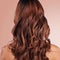Beauty, back and hair care of woman in studio isolated on a red background for haircare. Curly hairstyle, keratin