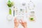 Beauty blog concept. Female hands touch smartphone screen on the background of styled greenery and white datails and accessories o