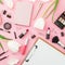 Beauty blogger composition with clipboard, flowers, cosmetics and accessory isolated on pink. Top view