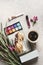 Beauty blogging setting with handbag, baguette, coffee, make up palette, lipstick, flowers and journal. Feminine freelancer