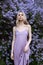 Beauty blonde woman in summer in a lilac Bush. Beauty Portrait of a girl in purple flowers, beautiful makeup